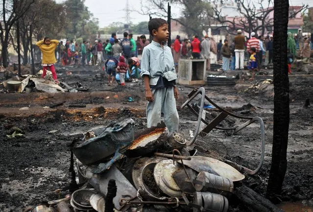 A boy stands amidst the charred remains of his home destroyed in a fire that broke out in a slum area in Jammu, November 26, 2016. (Photo by Mukesh Gupta/Reuters)