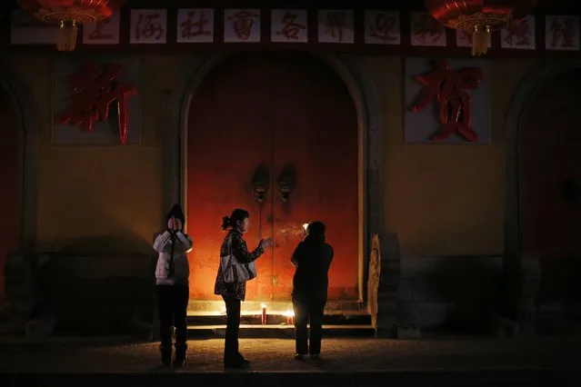 People burn incense as they pray for good fortune on the first day of the Chinese Lunar New Year at Jade Temple in Shanghai February 19, 2015. (Photo by Carlos Barria/Reuters)