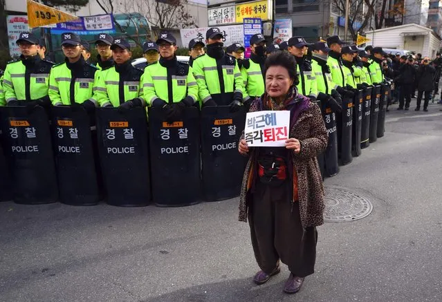 A South Korean protester holds a banner reading “Step down Park Geun-Hye!” in front of policemen during a protest outside the ruling Saenuri Party in Seoul on December 3, 2016. South Korea's opposition parties filed an impeachment motion against scandal-hit President Park Geun-Hye on December 3, as a fresh weekly protest was expected to draw a million protesters, organisers said. (Photo by Jung Yeon-Je/AFP Photo)
