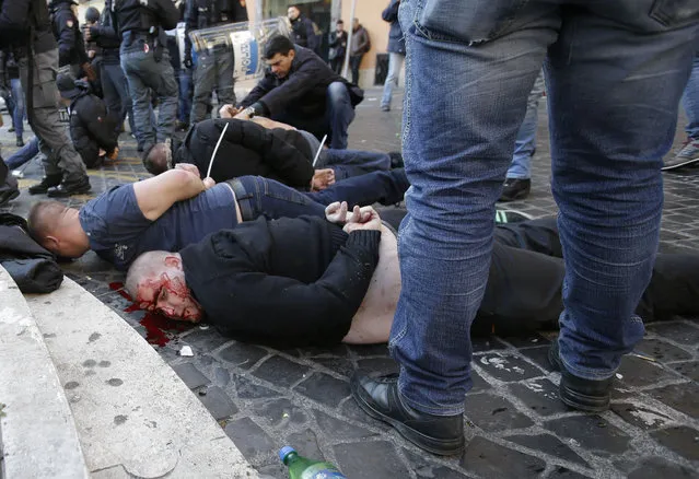 An injured Feyenoord's fan lies on the ground after being arrested with others during clashes occurred with Italian Policemen at the Spanish steps prior to the start of the Europa League soccer match between Roma and Feyenoord in Rome, Thursday, February 19, 2015. (Photo by Gregorio Borgia/AP Photo)