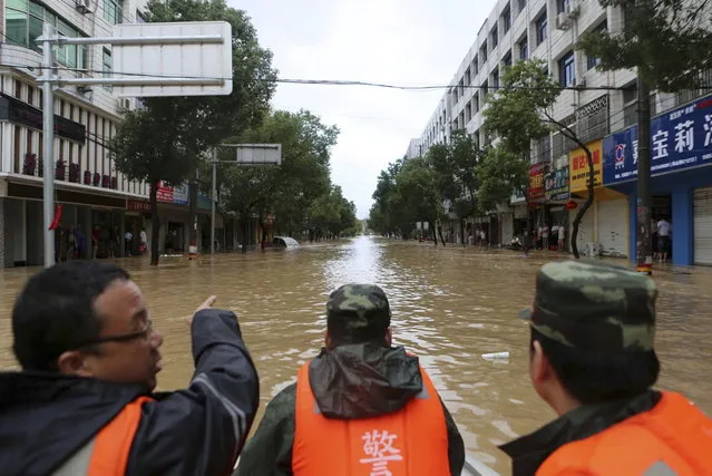 Rescuers talk on a boat as they travel along a flooded street after Typhoon Fitow hit Taoshan township of Rui'an, Zhejiang province October 7, 2013. Typhoon Fitow has affected the lives of 4.56 million people in east China's Zhejiang and Fujian provinces, the State Flood Control and Drought Relief Headquarters said on Monday, Xinhua News Agency reported. (Photo by Reuters/Stringer)