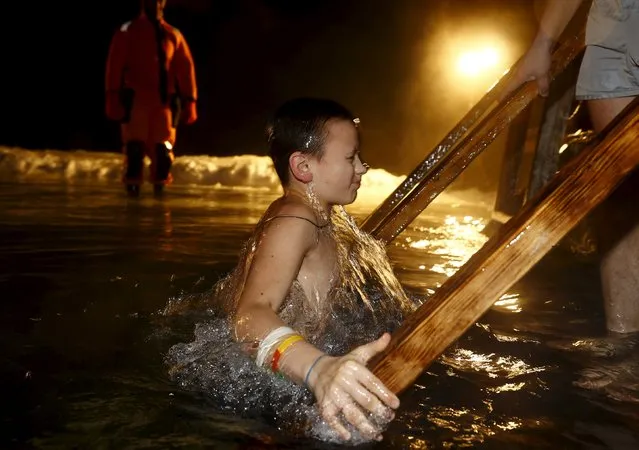 A boy dips into the icy waters of a lake as part of celebrations for Orthodox Epiphany on the outskirts of Minsk, January 18, 2016. (Photo by Vasily Fedosenko/Reuters)