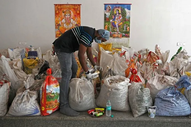 A volunteer can be seen sorting unclaimed sacks filled with ashes left after the cremation of the bodies of Covid-19 coronavirus fatalities at a crematorium in New Delhi on May 15, 2021. (Photo by Arun Sankar/AFP Photo)