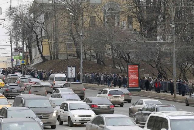 People stand in line to attend a memorial service before the funeral of Russian leading opposition figure Boris Nemtsov, with vehicles driving nearby, in Moscow, March 3, 2015. Several hundred Russians, many carrying red carnations, queued on Tuesday to pay their respects to Boris Nemtsov, the Kremlin critic whose murder last week showed the hazards of speaking out against Russian President Vladimir Putin. REUTERS/Maxim Shemetov 