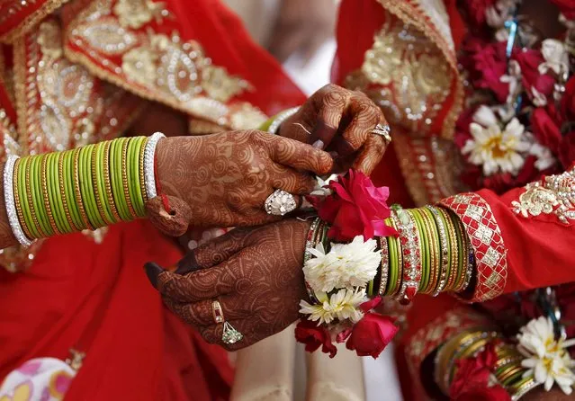A Muslim bride ties a flower on the wrist of another bride during a mass wedding ceremony in Ahmedabad, India, January 22, 2016. A total of 111 Muslim couples from various parts of Ahmedabad took their wedding vows on Friday during the mass marriage ceremony organised by a Muslim voluntary organisation, organisers said. (Photo by Amit Dave/Reuters)