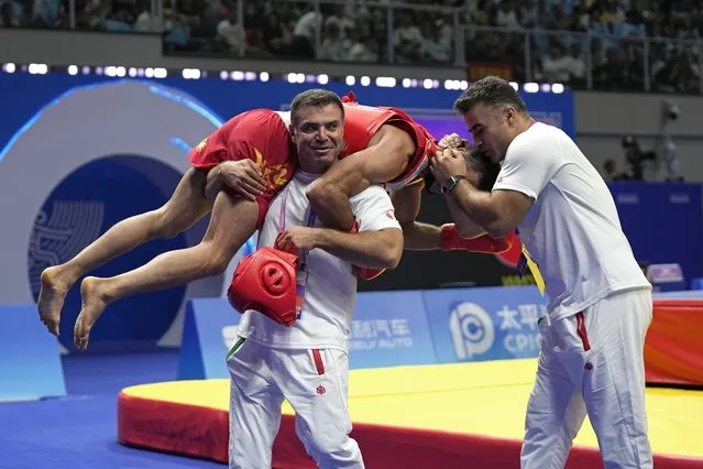Iran's Afshin Salimi Toupghara is carried by team coach Mohammad Ojaghi as they celebrate Toupghara's win against Indonesia's Samuel Marbun in the Wushu men's 65kg final at 19th Asian Games in Hangzhou, China, Thursday, September 28, 2023. (Photo by Aijaz Rahi/AP Photo)
