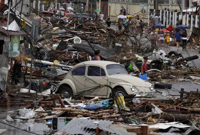 Typhoon victims sift through the debris Tuesday, November 12, 2013 in Tacloban city in Leyte province, central Philippines. Four days after Typhoon Haiyan devastated islands in the central Philippines, survivors are desperate for food and clamoring to be evacuated. (Photo by Bullit Marquez/AP Photo)