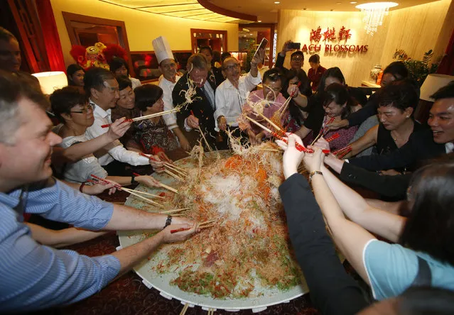 Guests toss an 88 kg plate of yusheng or raw fish during a “lo hei” dinner ahead of the Lunar New Year in Singapore January 8, 2016. (Photo by Edgar Su/Reuters)