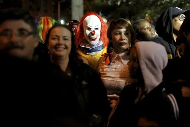 A person dressed in a clown costume stands amongst attendees during the Greenwich Village Halloween Parade in Manhattan, New York, U.S., October 31, 2016. (Photo by Andrew Kelly/Reuters)