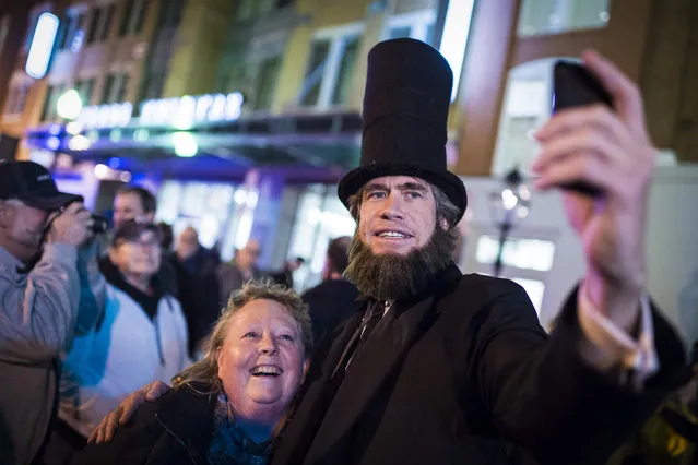 Scott Stewart dressed as Abraham Lincoln takes selfies with Susan Squires before a candlelight vigil where living historians recreated the scene from the night of April 14, 1865 on Tenth Street NW to commemorate the 150th anniversary of President Lincoln's assassination outside Ford's Theatre in Washington, DC on Tuesday April 14, 2015. (Photo by Jabin Botsford/The Washington Post)