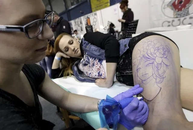 An artist draws a tattoo on a woman's leg during a tattoo convention in Ljubljana April 18, 2015. (Photo by Srdjan Zivulovic/Reuters)