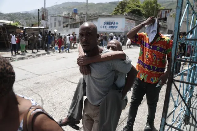 An elderly man is carried as residents flee their homes to avoid clashes between armed gangs in the Carrefour-Feuilles district of Port-au-Prince, Haiti, Tuesday, August 15, 2023. (Photo by Odelyn Joseph/AP Photo)