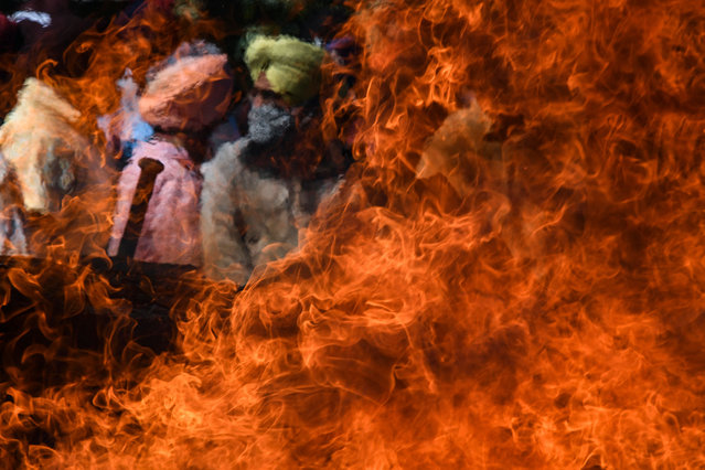 People stand around the funeral pyre of slain government school principal Supinder Kour at a cremation ground in Srinagar on October 8, 2021, a day after suspected anti-India militants shot dead two school teachers in Indian-administered Kashmir. (Photo by Tauseef Mustafa/AFP Photo)