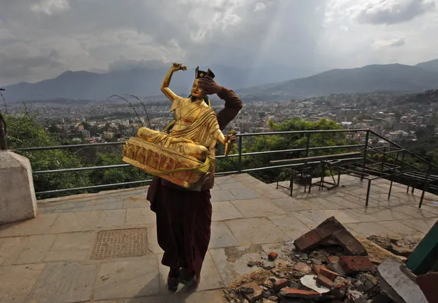 A Buddhist monk salvages a statue of a Buddhist deity from a monastery around the famous Swayambhunath stupa after it was damaged by Saturday's earthquake in  Kathmandu, Nepal, Thursday, April 30, 2015. In mere seconds, Saturday's earthquake devastated a swathe of Nepal. Three of the seven World Heritage sites in the Kathmandu Valley have been severely damaged, including Durbar Square with pagodas and temples dating from the 15th to 18th centuries, according to UNESCO, the United Nations cultural agency. (Photo by Niranjan Shrestha/AP Photo)
