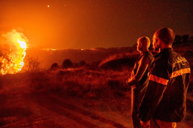 Civil Defense personnel monitor a wildfire burning through hills on July 28, 2021 in Qobayat, Lebanon. A Lebanese teenager was killed as he joined volunteers battling to fight the fire. (Photo by Ethan Swope/Getty Images)
