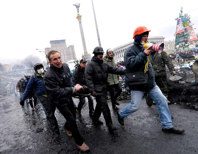 Anti-government protesters carry a fellow demonstor who was wounded during clashes with riot police in central Kiev on February 20, 2014. (Photo by Sergei Supinsky/AFP Photo)