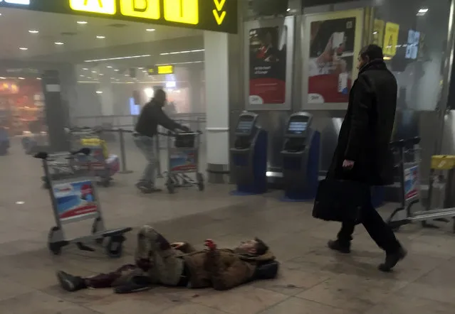 In this photo provided by Georgian Public Broadcaster and photographed by Ketevan Kardava, an injured man lies on the floor in Brussels Airport in Brussels, Belgium, after explosions were heard Tuesday, March 22, 2016. A developing situation left a number dead in explosions that ripped through the departure hall at Brussels airport Tuesday, police said. All flights were canceled, arriving planes were being diverted and Belgium's terror alert level was raised to maximum, officials said. (Photo by Ketevan Kardava/Georgian Public Broadcaster via AP Photo)