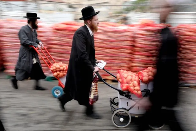 Ultra-Orthodox Jews carry potato sacks during food distribution in the Mea Shearim neighborhood of Jerusalem, Israel, 16 April 2019. The food was provided by charity organizations for people in need ahead of the Jewish holiday of Passover. (Photo by Abir Sultan/EPA/EFE)