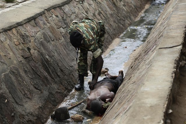 A Soldiers check the vital signs of a wounded suspected Imbonerakure militiaman who was attacked by demonstrators protesting against President Pierre Nkurunziza's decision to seek a third term in office in the Cibitoke district of Bujumbura, Burundi, Thursday May 7, 2015. (Photo by Jerome Delay/AP Photo)
