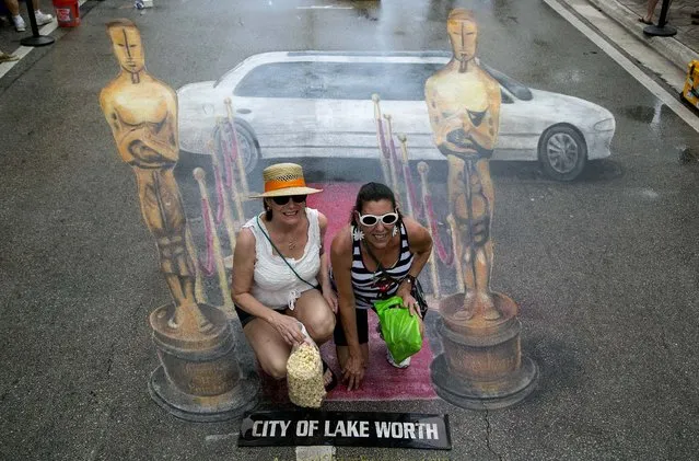 Gabrielle Mathews, of Lake Worth, and Martine Demler, of Boynton Beach, pose for photos on the red carpet of a rain soaked version of the the Academy Awards red carpet, created by artist Jennifer Chaparro. (Photo by Greg Lovett/The Palm Beach Post)