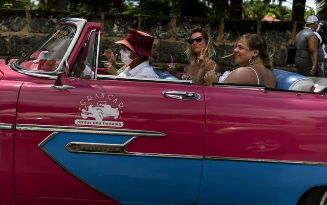 Tourists enjoy a mojito while traveling in a vintage American car during a city tour of Varadero, Cuba, Wednesday, September 29, 2021. Authorities in Cuba have begun to relax COVID restrictions in several cities like Havana and Varadero. (Photo by Ramon Espinosa/AP Photo)