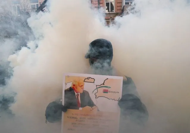 Ukrainian activists of the “National resistance” movement burn smoke grenades during a rally near the Belarusian embassy in Kiev, Ukraine, 10 November 2021. Protesters gathered to protest against the attempt of Belarusian President Alexander Lukashenko to terrorize Poland and the EU with illegal immigrants and possible redirection of Immigrants to Ukraine as activists told. According to the State Border Committee of Belarus (GPK), there are more than two thousand people near the Belarus-Polish border, including women and children, who want to obtain asylum in the European Union. Several thousand employees of the Polish special services guard the EU border. The migration crisis at the border of Belarus has been going on since the spring of 2021. Belarusian President Lukashenko said that after the introduction of new EU sanctions against Minsk, the Belarusian authorities will no longer interfere with the movement of illegal migrants to the European Union. (Photo by Sergey Dolzhenko/EPA/EFE)
