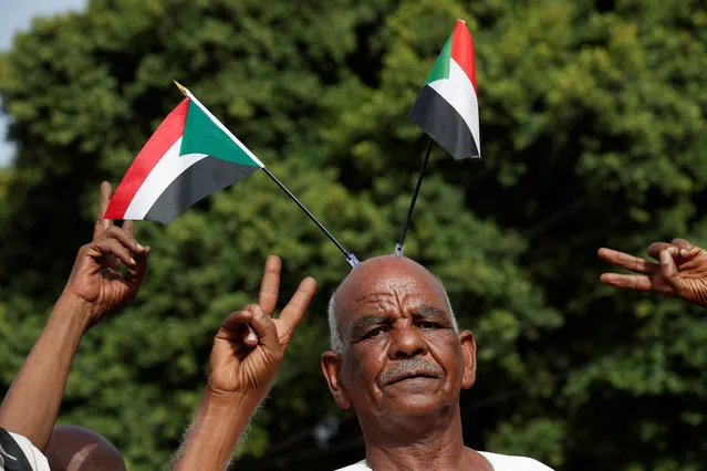 Protesters make victory signs as one of them carry Sudanese flags on his head during a demonstration in front of the Defence Ministry in Khartoum, Sudan, April 18, 2019. (Photo by Umit Bektas/Reuters)