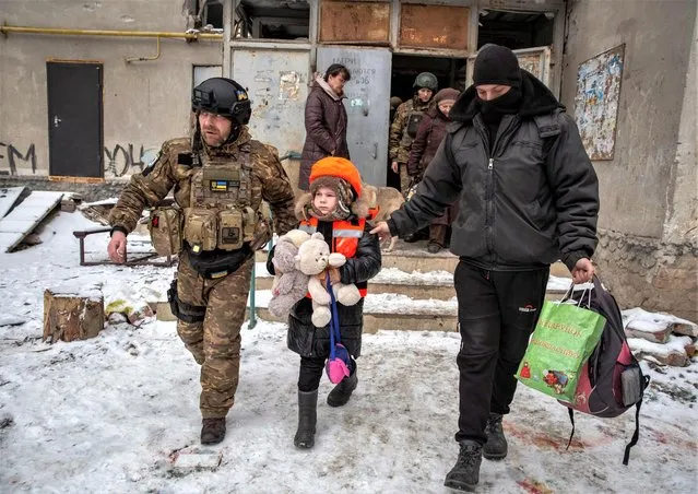 Policemen help Arina, 6, dressed in children's bulletproof vest and helmet during her evacuation from front line city of Bakhmut, amid Russia's attack on Ukraine, in Donetsk region, Ukraine on January 31, 2023. (Photo by Oleksandr Ratushniak/Reuters)