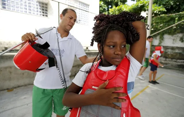 A fencing instructor helps a child from municipal school Parana during the project “Fencing School” in Rio de Janeiro, Brazil, March 30, 2016. (Photo by Sergio Moraes/Reuters)