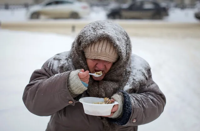 A woman eats during a charity event organised to distribute meals for homeless and poor people near a cathedral in southern city of Stavropol, Russia January 29, 2017. (Photo by Eduard Korniyenko/Reuters)