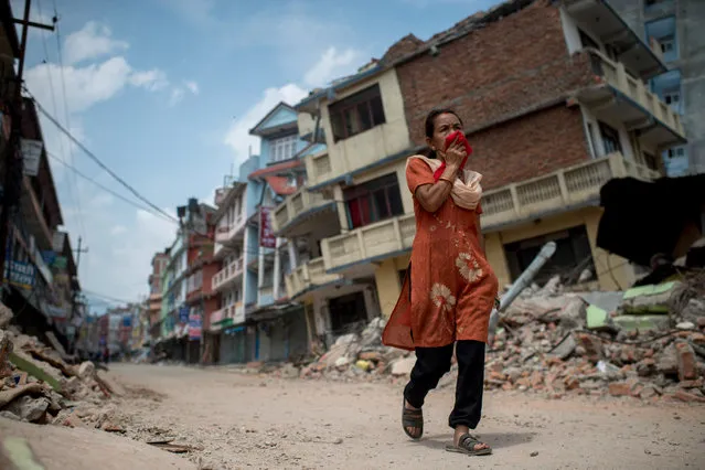 People walk past the rubble of destroyed buildings following a second major earthquake May 13, 2015 in Kathmandu, Nepal. A 7.3 magnitude earthquake struck in Nepal only two weeks after more than 8,000 people were killed in a devastating earthquake. The latest quake struck near Mt Everest near the town of Namche Bazar. Tremors were felt as far away as Bangladesh and Delhi. (Photo by Jonas Gratzer/Getty Images)