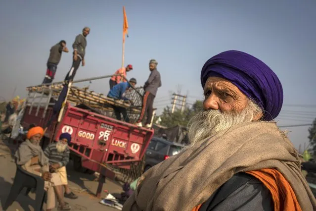 An elderly Sikh farmer looks on as others dismantle temporary structures used during protests in Singhu, on the outskirts of New Delhi, India, Saturday, December 11, 2021. Tens of thousands of jubilant Indian farmers on Saturday cleared protest sites on the capital's outskirts and began returning home, marking an end to their year-long demonstrations against agricultural reforms that were repealed by Prime Minister Narendra Modi's government in a rare retreat. (Photo by Altaf Qadri/AP Photo)