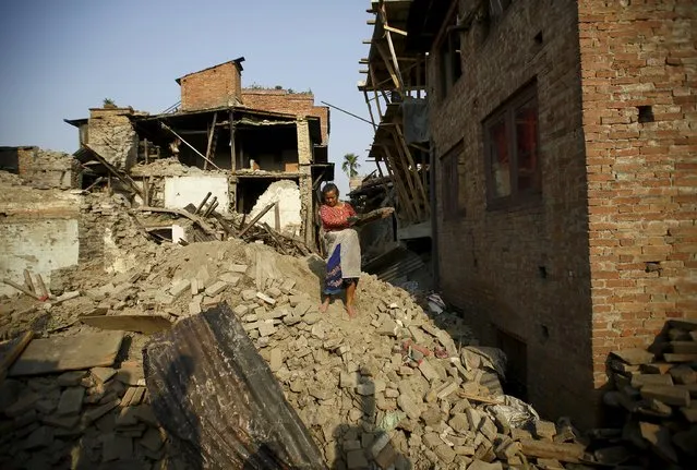 A woman carrying blocks of wood recovered from her house walks along debris of collapsed houses, a month after the April 25 earthquake in Kathmandu, Nepal May 25, 2015. (Photo by Navesh Chitrakar/Reuters)