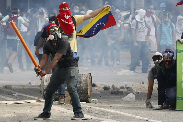 Anti-government demonstrators pretend to bat gas canisters to police during riots in Caracas April 1, 2014. Venezuelan troops dispersed opposition demonstrators with teargas on Tuesday and blocked anti-government activist Maria Corina Machado, recently stripped of her seat in the National Assembly, from reaching the legislature. (Photo by Christian Veron/Reuters)
