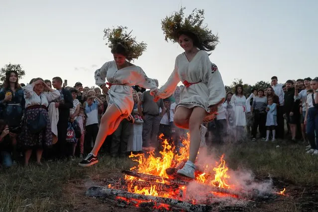 Ukrainians jump over a bonfire in Kiev, Ukraine, 06 July 2019, as they celebrate the traditional pagan holiday of Ivana Kupala. Ivana Kupala is celebrated, during the summer solstice, on the shortest night of the year, marking the beginning of summer and is celebrated in Ukraine, Belarus, Poland and Russia. People sing and dance around bonfires, play games and perform traditional rituals. Young people jump over bonfires in order to test their bravery. Couples holding hands jump over the flames to test their love. If the couple does not succeed it is predicted to split up. Traditionally, children and young unmarried women wear wreaths of wild flowers on their heads to symbolize purity. (Photo by Sergey Dolzhenko/EPA/EFE)