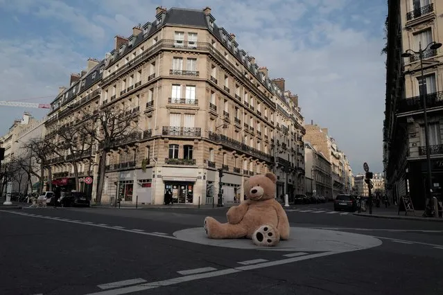 A teddy bear placed on a traffic roundabout by Philippe Labourel, who wants to be named “Le papa des nounours”, “Teddy Bear father”,  in Paris, Wednesday, March 3, 2021. Philippe Labourel, a bookshop owner, situated in the Gobelins district of Paris, has been lending out oversized plush creatures since October 2018, Since the pandemic cut short public life in the French capital last year, the bookseller's bears have been spotted sitting at a bus stop and in shops to remind customers of social distancing rules. (Photo by Francois Mori/AP Photo)