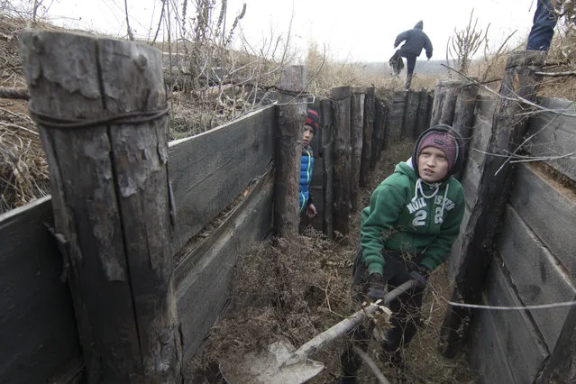 Children from an orphanage volunteer to help the city defenders to strengthen trenches on Ukraine's Army positions near the village of Rybatske 25 km from Mariupol, Ukraine, Monday, November 26, 2018. Ukrainian lawmakers were set to consider a presidential request for the introduction of martial law in the country on Monday following an incident in which Russian coast guard ships fired on Ukrainian navy vessels. (Photo by Sergey Vaganov/AP Photo)