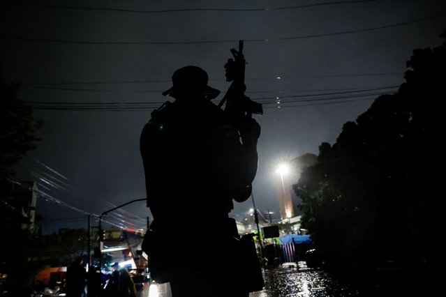 A police officer holds a rifle while patrolling on a boat in a flooded area to prevent theft in the downtown of Porto Alegre,Rio Grande do Sul state, Brazil on May 12, 2024. (Photo by Adriano Machado/Reuters)
