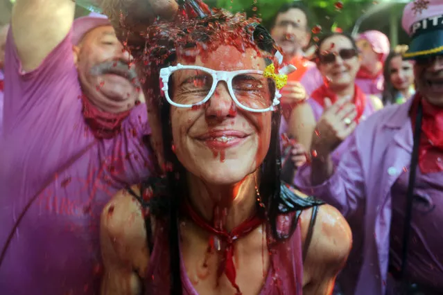 A man pours red wine on a girl's head during the Batalla del Vino (Battle of Wine) in Haro, on June 29, 2015. Every year thousands of locals and tourists climb a mountain in the northern Spanish province of La Rioja to celebrate St. Peter's day covering each other in red wine while tanker trucks filled with wine distribute the alcoholic beverage to water pistols, back mounted spraying devices, buckets which are randomly poured on heads and into any other available container. (Photo by Cesar Manso/AFP Photo)