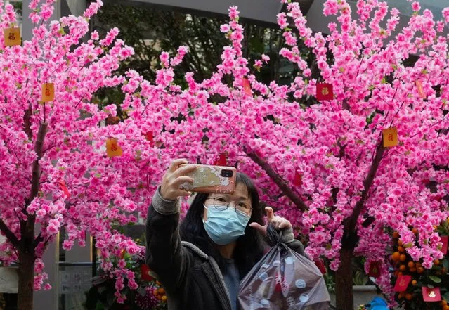 A woman takes a selfie in front of decorations to celebrate the Lunar New Year in Hong Kong, Sunday, January 30, 2022. The Chinese Lunar New Year falls on Feb. 1. (Photo by Vincent Yu/AP Photo)