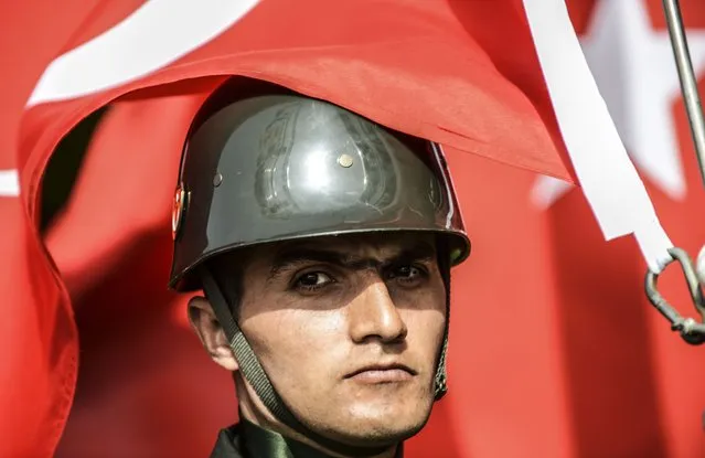 A Turkish flag partially covers the face of a Turksih soldier standing during the ceremony celebrating the 99th anniversary of the Anzac Day in Canakkale on April 24, 2014. A dawn ceremony on April 25 marks the time of the first landings of the Australian and New Zealand Army Corps (ANZAC) at the Gallipoli peninsula in the ill-fated Allied campaign to take the Dardanelles Strait from the Ottoman Empire. (Photo by Bulent Kilic/AFP Photo)