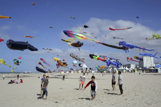 Boys play soccer as kites are seen in the sky during the 31st International Kite Festival in Berck, northern France, Thursday, April 6, 2017. The International Kite Festival is organized in Berck-sur-Mer every April and lasts for 10 days. (Photo by Thibault Camus/AP Photo)