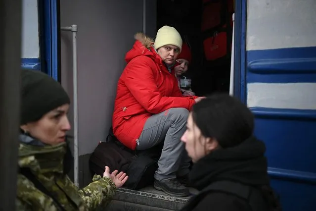 People sit on a corridor as they have no space in a train which prepares to depart from a station in Lviv, western Ukraine, enroute to Poland, on March 3, 2022. Russian forces have taken over the Ukrainian city of Kherson, local officials confirmed March 2, 2022 the first major urban centre to fall since Moscow invaded a week ago. (Photo by Daniel Leal/AFP Photo)