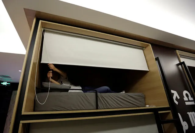 Zhang Shuangjie, an IT engineer at BaishanCloud, drops the curtain as he prepares to sleep around midnight in an individual sleeping quarter, in the office, in Beijing, China, April 26, 2016. (Photo by Jason Lee/Reuters)