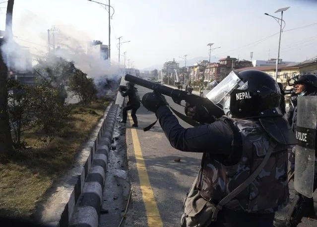 A Nepalese policeman fires tear gas as protesters opposing a proposed U.S. half billion dollars grant for Nepal clash with them as the parliament debates the contentious aid in Kathmandu, Nepal, Sunday, February 20, 2022. (Photo by Niranjan Shreshta/AP Photo)