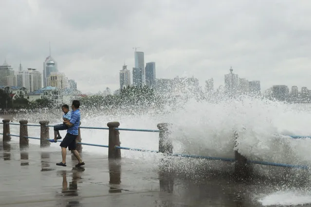 A man carrying a child runs away from massive waves hit the seacoast of Qingdao in east China's Shandong province Sunday, July 12, 2015. A typhoon pounded the Chinese coast south of Shanghai on Saturday with strong winds and heavy rainfall, submerging roads, felling trees and forcing the evacuation of people. (Photo by Chinatopix via AP Photo)