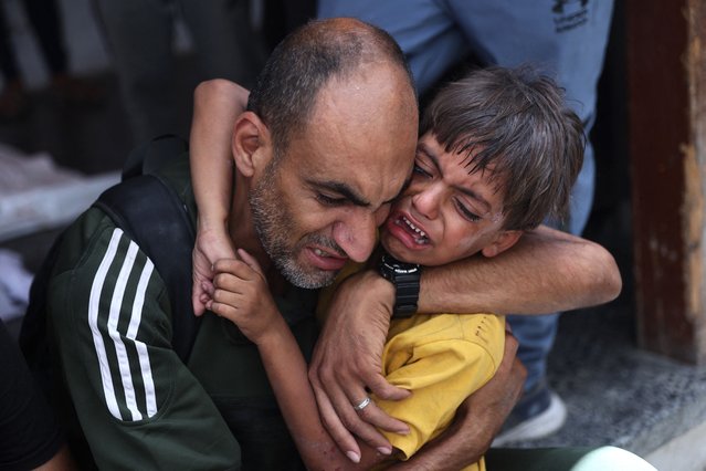 A Palestinian child is comforted as he stands near a body bag (unseen) following Israeli bombardment of a Gaza City neighbourhood, at Al-Ahli Arab hospital, also known as the Baptist hospital in Gaza City on July 4, 2024, amid the ongoing conflict between Israel and the Palestinian Hamas militant group. (Photo by Omar Al-Qattaa/AFP Photo)