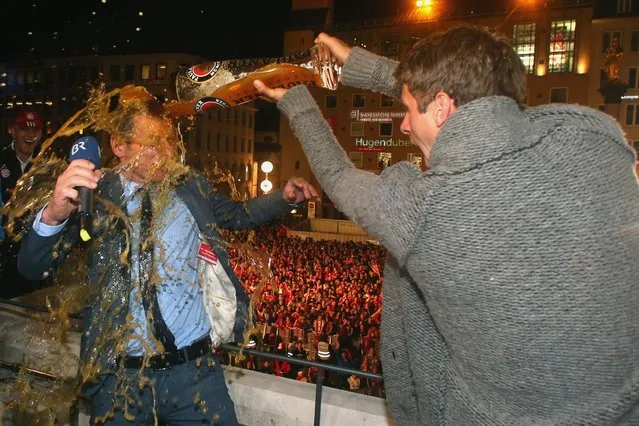Bayern Munich's midfielder Thomas Mueller (R) pours beer over TV presenter Markus Othmer on the balcony of Munich's city hall during celebrations of the German football league title on May 10, 2014 in Munich, southern Germany. Players and team members of the club celebrated together with their supporters at Marienplatz square in the center of the Bavarian capital. (Photo by Alexander Hassenstein/AFP Photo)