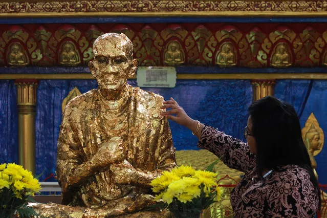 A devotee put a golden paper  onto  Buddha statue during Vesak day in Penang, Malaysia, on May 10,2017. Buddhists around the world have celebrate Vesak ,one of the most important day in Buddhist calendar informally known as Buddha 's birthday, it commemorates the birth, enlightenment and the death of Buddha, Siddhartha Gautama.Buddhist scriptures state that each occurred on the full moon of the Indian lunar month of Vesakha.Buddhists celebrate Vesak every year on the day of full moon in May. (Photo by Shaiful Azre/NurPhoto via Getty Images)