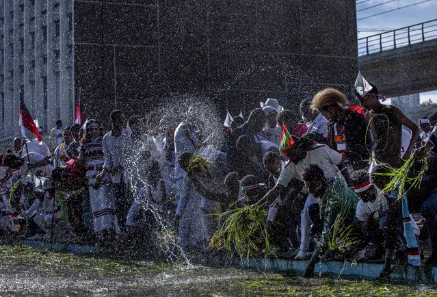 Ethiopians throw grass into a pool of water, as a symbol of riches after the rainy season and to thank the land and water for everything they have provided, as they celebrate the annual Irrecha thanksgiving festival in the capital Addis Ababa, Ethiopia Saturday, October 5, 2019. The annual Irrecha festival of Ethiopia's largest ethnic group, the Oromo, attracted millions from across Ethiopia and was held in the capital for the first time after 150 years on Saturday. (Photo by Mulugeta Ayene/AP Photo)